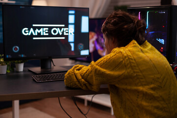 Angry streamer losing space shooter videogames during online entertainment competition at home in living room. Game over on computer screen. Player performing cybersport championship © DC Studio