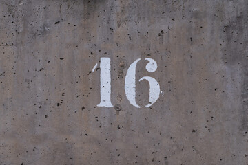 number 16 drawn on a perforated cement wall