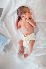 Top view of a newborn baby in hospital bed. The baby sleeps soundly.
