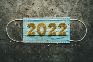 New Years Eve celebration concept background. Medical mask with the numbers 2022. Covid-19 New Year concept