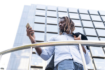 Black young man with dreadlocks checking message in cellphone