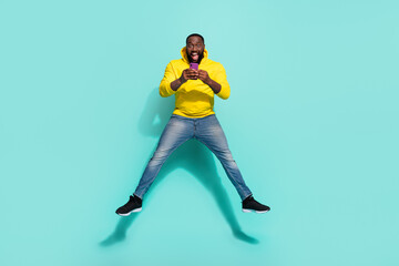 Full body photo of carefree guy jump typing chat bargain web news isolated over cyan color...