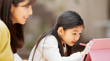 タブレットパソコンで勉強する女の子とその母親