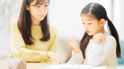 母親に勉強を教えてもらっている娘