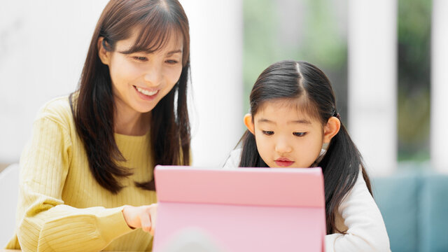 タブレットパソコンで勉強する女の子とその母親