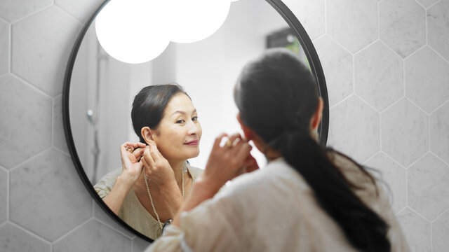 イヤリングを付けるシニア女性