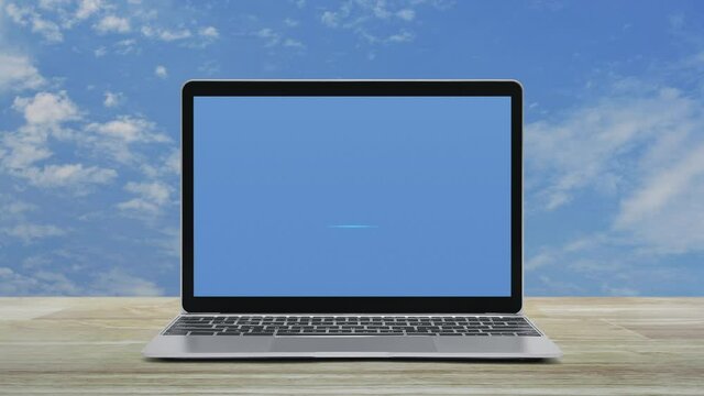 Download flat icon on modern laptop computer screen on wooden table over blue sky with white clouds, Technology internet online concept