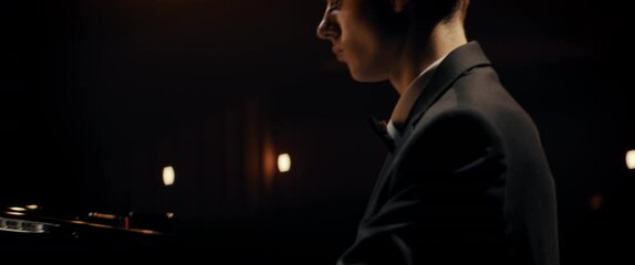 PORTRAIT of Young 20s aspiring musician playing grand piano on a stage of a huge concert hall. Shot with 2x anamorphic lens - Powered by Adobe
