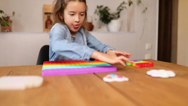 Happy emotional, hyperactive little girl playing with big silicone popit, simple dimple, bubble fidget toy, antistress sensory toy at home, make faces. The concept of mental health popit toy