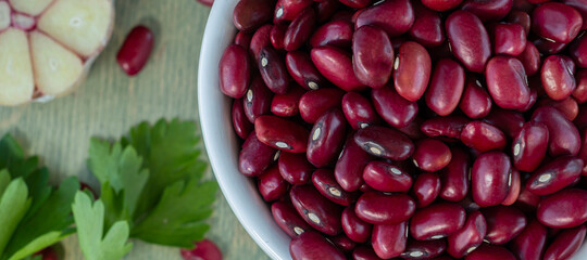 banner with close-up of red beans in a white cup with spices on a wooden table.