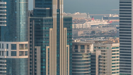 Skyscrapers of Dubai with a lot of ships in port behind aerial timelapse