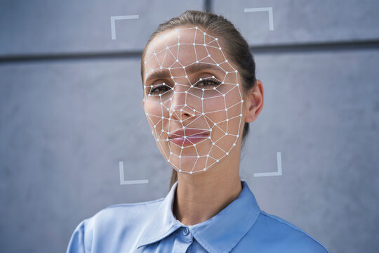 Businesswoman with facial recognition biometrics in front of wall