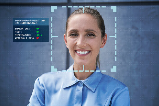 Smiling businesswoman with facial recognition technology in front of wall