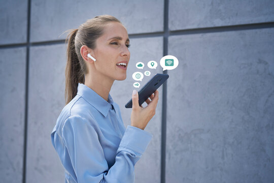 Businesswoman with wireless in-ear headphones talking mobile phone