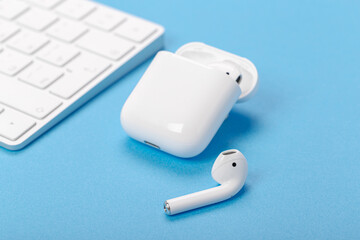 wireless bluetooth earphones with charging case on a blue background. The concept of modern...