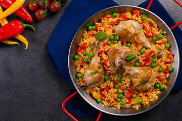 Arroz con pollo. Baked pieces of chicken with bone, rice with paprika and peas.