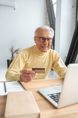 Mature man wearing glasses making online purchase using credit card