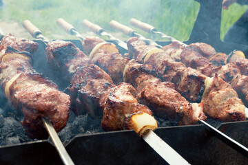 Marinated shashlik preparing on a barbecue grill over charcoal. Shashlik or Shish kebab popular in...