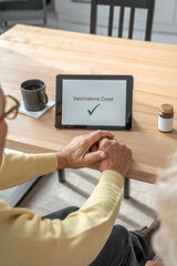 Senior couple sitting in front of tablet while received covid vaccination certificate