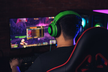 Guy in green headphones playing video games on an armchair