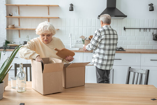 Happy elderly couple unpacking carton boxes in their new house - Powered by Adobe