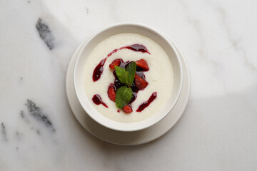 Semolina porridge with strawberries on a white table