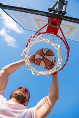 dunk in basket. slam dunk in motion. summer activity. energetic man with basketball ball