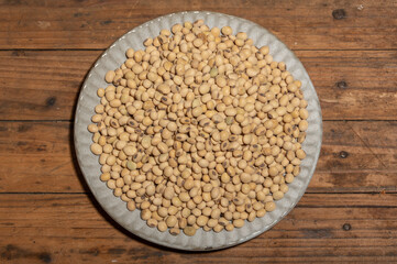 Soybeans placed in a bowl or plate are on the wood grain table
