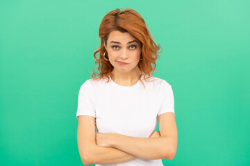 confused redhead woman with curly hair on blue background crossed hands, emotions