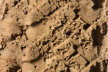 detailed filled frame background close up shot of car tire tracks, prints and marks on a muddy dusty sand road surface