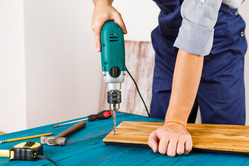 Handyman in blue uniform works with electricity automatic screwdriver