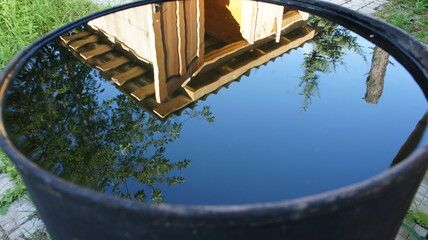 Reflection of a house in a barrel of water