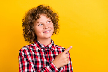 Photo of lovely orange hairdo teenager boy indicate empty space wear red checkered shirt isolated on yellow color background