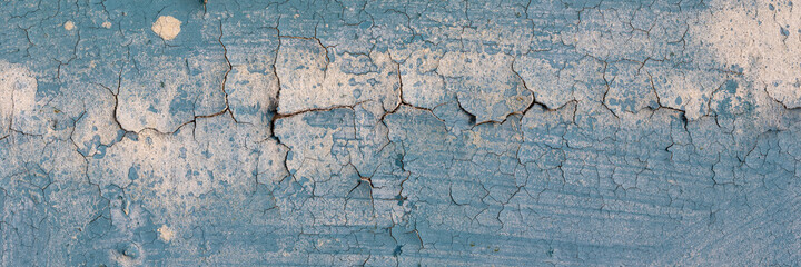 Peeling paint on the wall. Panorama of a concrete wall with old cracked flaking paint. Weathered rough painted surface with patterns of cracks and peeling. Grunge texture for wide panoramic background