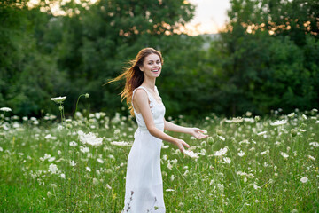 cheerful woman in a field with flowers in a white dress in nature