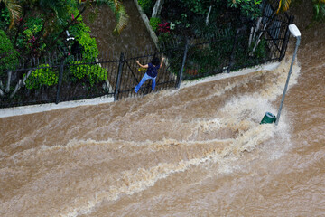 Woman try to cross a flooded avenue during an extremely heavy rain in downtown Sao Paulo, Brazil.