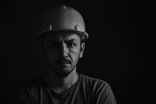 Portrait miner in helmet and undershirt with dirty face.