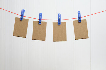 Cardboard cards are hung by clothespins on white background, template for inscription.