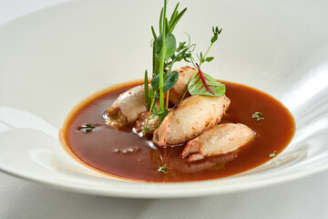 Stuffed squid in sauce in a white plate on a white tablecloth