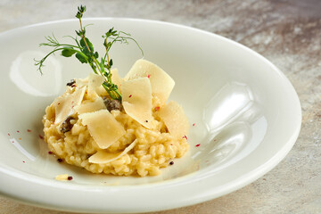 Appetizing risotto with porcini mushrooms and parmesan in a white plate on a white tablecloth