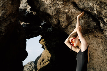 woman in black swimsuit posing near rocks ocean exotic