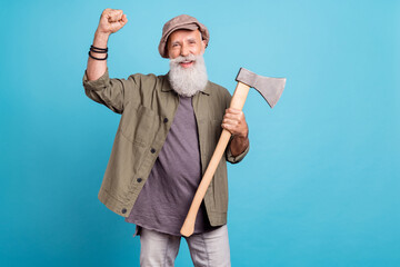 Photo of celebrate elder man wearing khaki shirt cap holding wooden ax isolated over vivid blue...