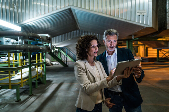 Businesswoman ans businessman discussing over digital tablet in industry