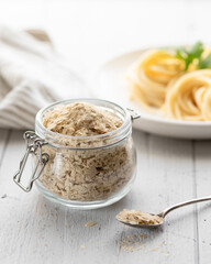 Nutritional yeast flakes in a glass jar , selective focus