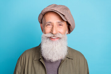 Photo of funky grey beard old man buy cap on resale wear khaki shirt isolated on blue color...