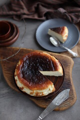 Basque burnt cheesecake in a plate on a wooden board. Cheesecake San Sebastian on a beige table.