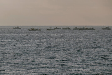A group of fishing boats lined up on the horizon off the coast of Livorno, Italy