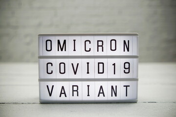 Omicron Covid19 Variant alphabet letter in Lightbox on wooden and white brick background