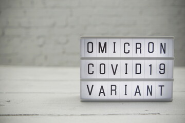 Omicron Covid19 Variant alphabet letter in Lightbox on wooden and white brick background