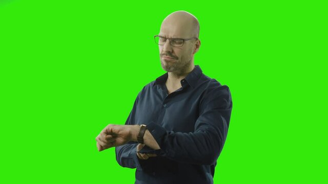 self-confident man looking at his watch in front of a greenscreen